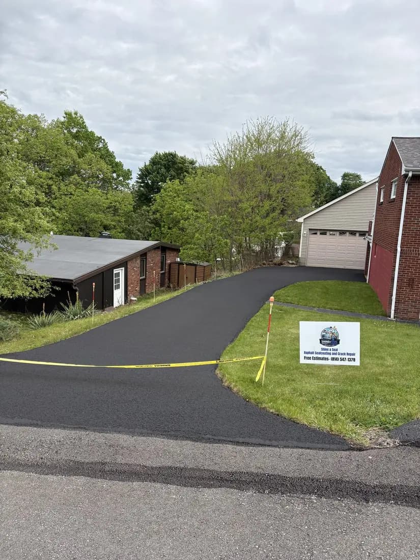 The same driveway freshly hand-sealed deep black, the day Tommy finished